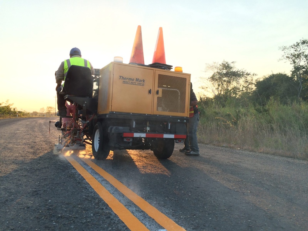 Equipo de señalamiento horizontal trabajando en carretera al atardecer