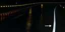 Marca vial con elementos cerámicos de noche bajo lluvia